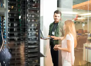 Photos de deux personnes discutant devant un serveur informatique